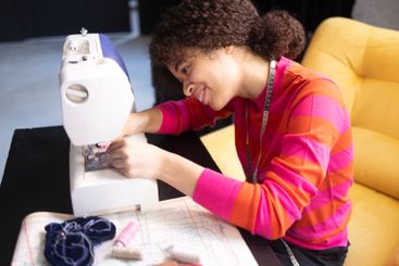 Young African woman working at sewing machine. Charming...