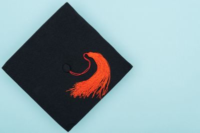 Top view of academic cap with red tassel isolated on blue