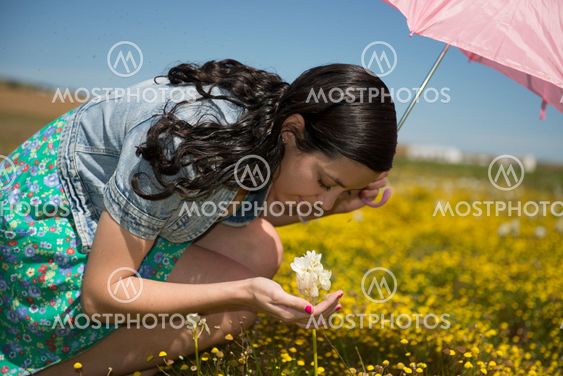 Beautiful adult smelling flowers on sunny field enjoying herself