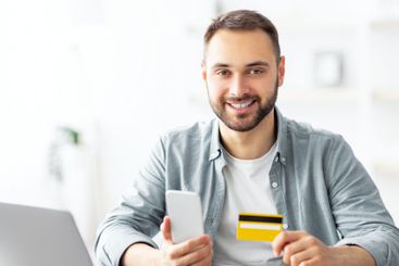 Happy young Caucasian man shopping online, using...