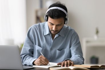 Male student in earphones listen to lecture on notebook...