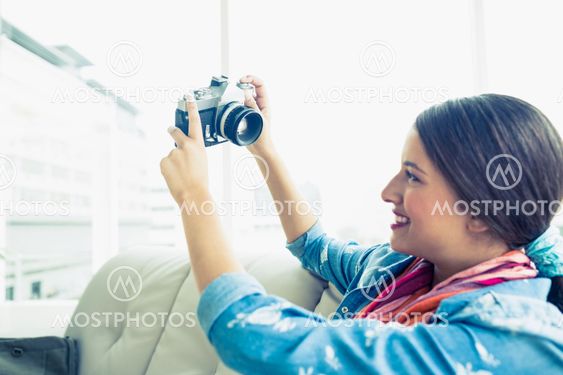 Young brunette sitting on sofa taking a selfie