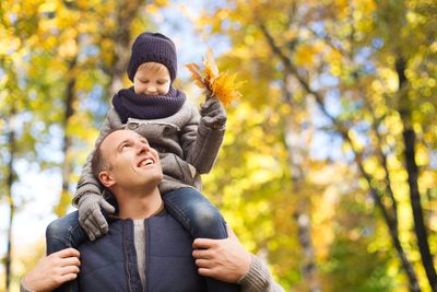 happy father carrying son with autumn maple leaves