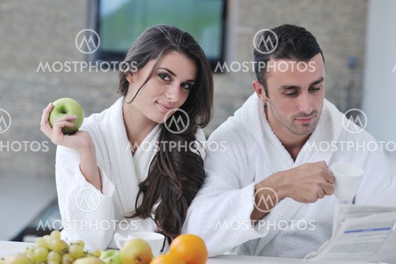 Happy couple reading the newspaper in the kitchen at breakfast