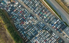 Aerial view of big parking lot of junkyard with rows of...