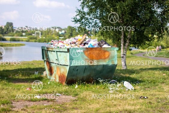 A large, metal, green and rusty container for garbage...