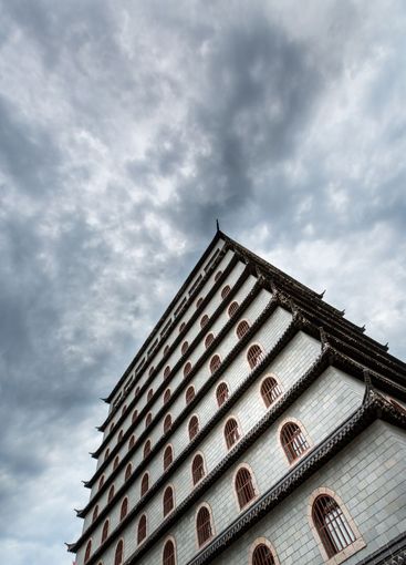 Kinesisk traditionell stenbyggnad och dramatisk himmel. 