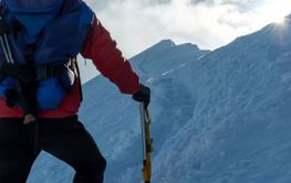 Mountaineer climbing a snowy ridge at sunrise.