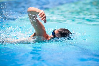 Young man swimming the front crawl in a pool