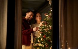 happy couple decorating christmas tree at home