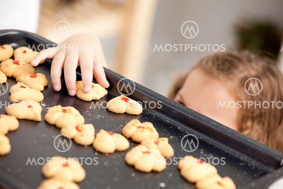 Close up of a little girl taking a cookie behind her mother's back