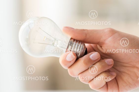 close up of hand holding edison lamp or lightbulb