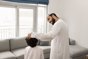 Positive Middle Eastern father cuddling little sons head