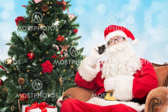 santa claus with smartphone and christmas tree
