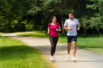 Cheerful couple friends running in park