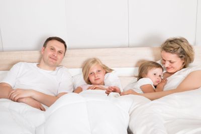 Young Family Lying Together In Bed