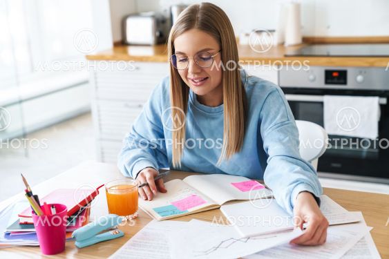 Image of focused woman smiling while studying with...