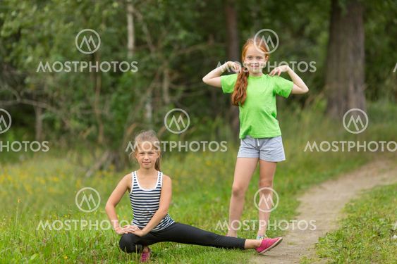Two little cute girls warming up outdoors. Morning...