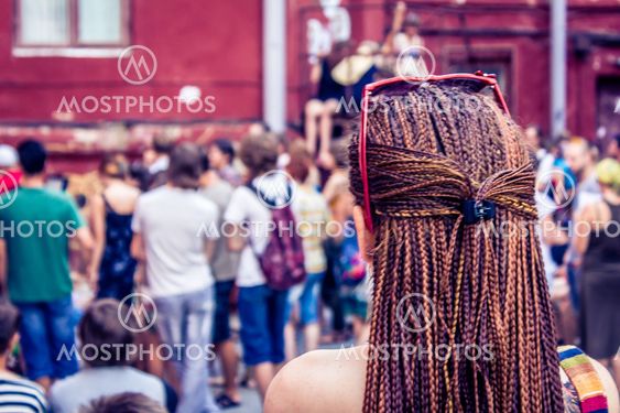 Girl with dreadlocks looks at the crowd of young people.