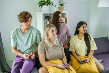 Cheerful group of friends playing video games together...
