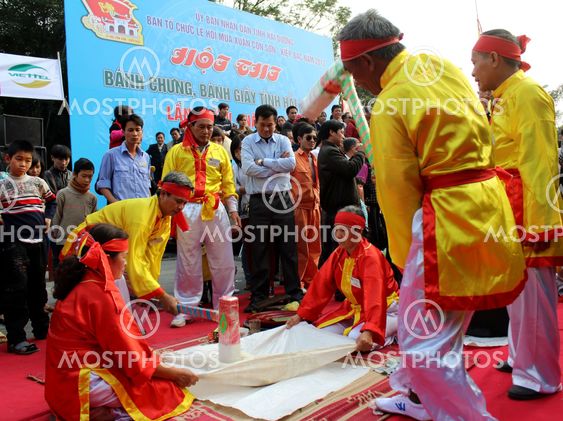 People in traditional costume exam to make round sticky...