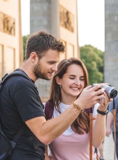 happy couple of travelers looking at photo camera at...