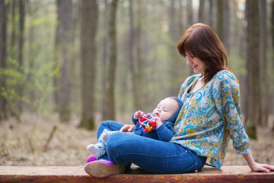 Young mother with her baby boy in forest