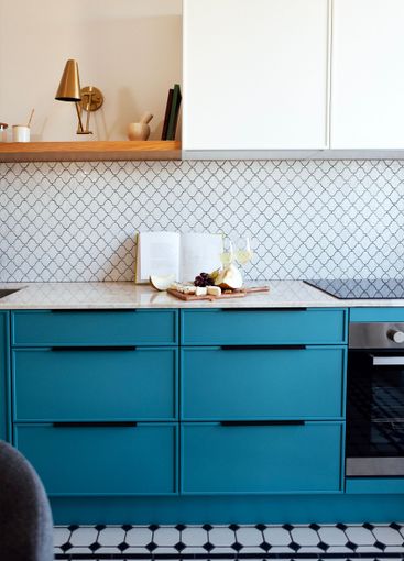 A modern kitchen with a blue set and a marble...