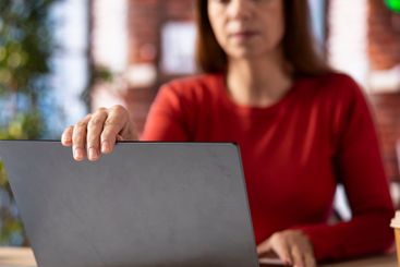 Casual woman opening her laptop at home office to solve...