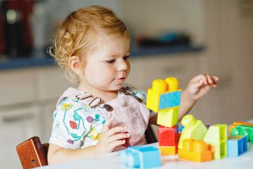 Adorable toddler girl with educational toys in nursery...