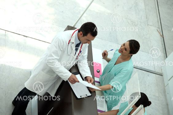 Medical secretary showing record to doctor