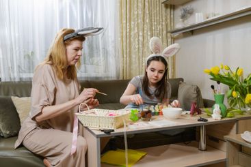 Mother And Daughter Decorating Easter Eggs At Home.