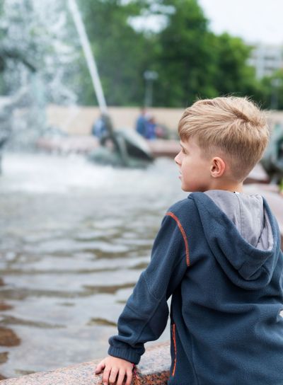 Blonde boy standing at a fountain