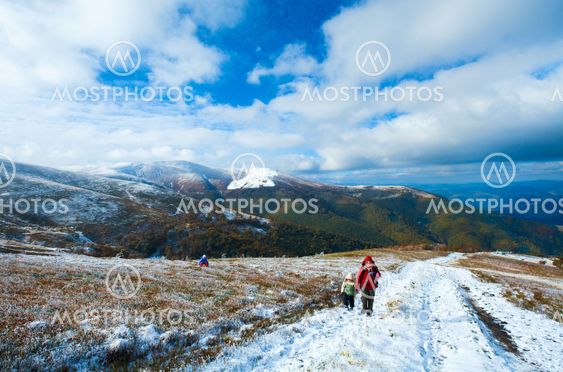 Family on autumn mountain plateau first winter snow