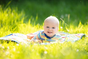 Baby boy with apple on family garden picnic