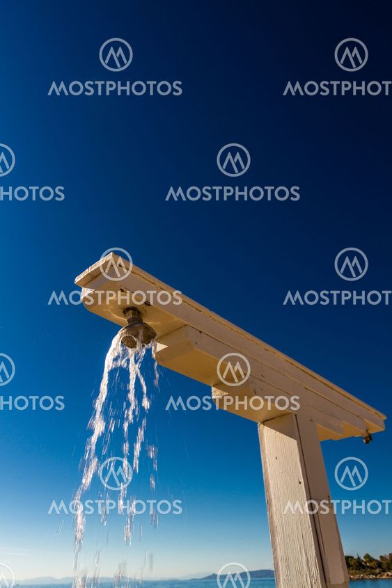 Beach shower, water flowing from it, portrait.