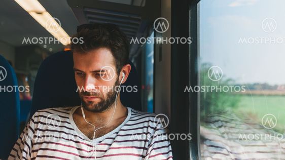 Young man traveling on a train listening to the music