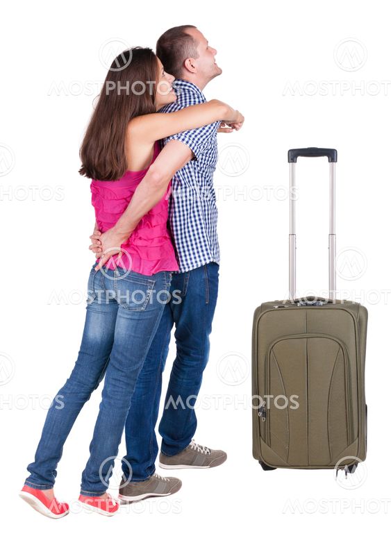 Back view of young couple traveling with suitcas .