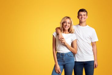 Portrait of happy millennial couple cuddling on yellow...