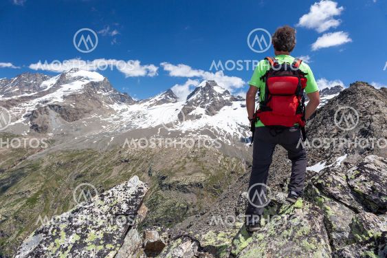 A hiker takes a rest looking at mountain panorama. Gran...