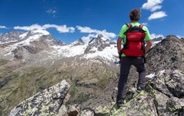 A hiker takes a rest looking at mountain panorama. Gran...