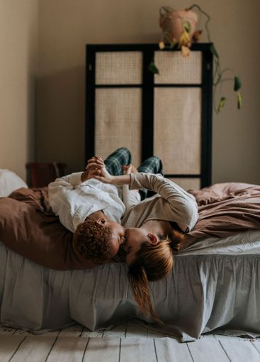 Romantic non-binary person kissing each other while lying...