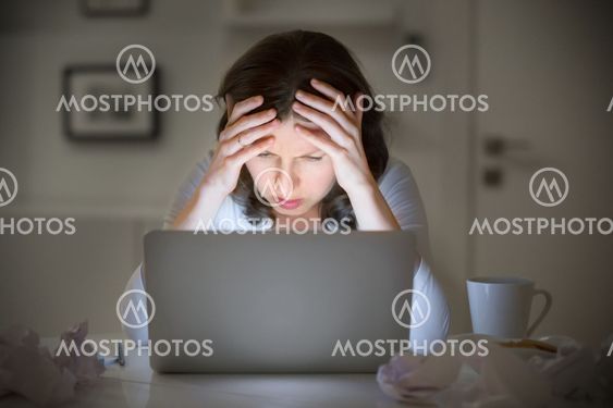 Portrait of a woman grabbing her head near the laptop