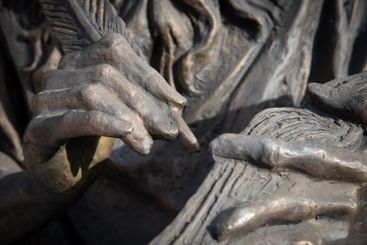 Bronze sculpture of hands holding a feather pen and...