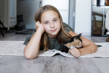 Cute young girl and cat pet together at home. Friendship...