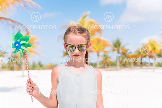 Little girl in hat walking at beach during caribbean...