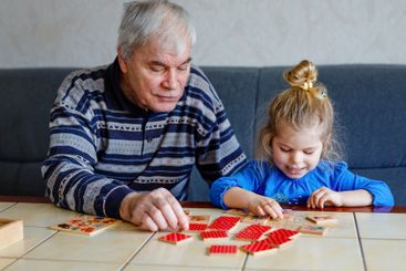 Beautiful toddler girl and grandfather playing together...
