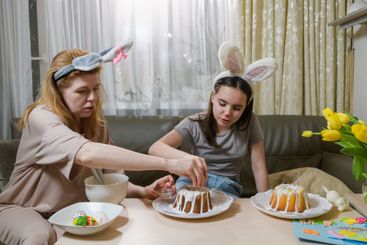 Mother and daughter decorating Easter cakes together.