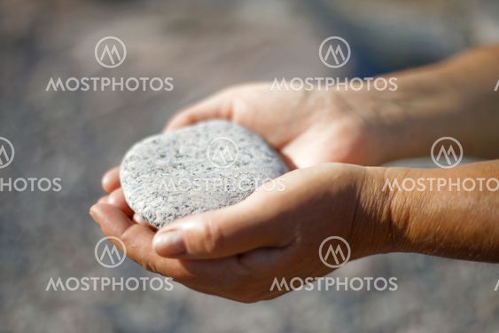 Closeup of female hands holding a stone in warm evening...
