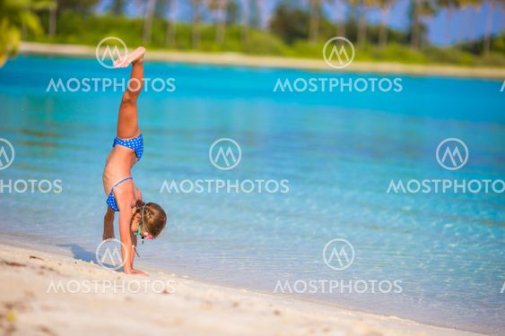 Adorable little girl having fun at beach during summer...